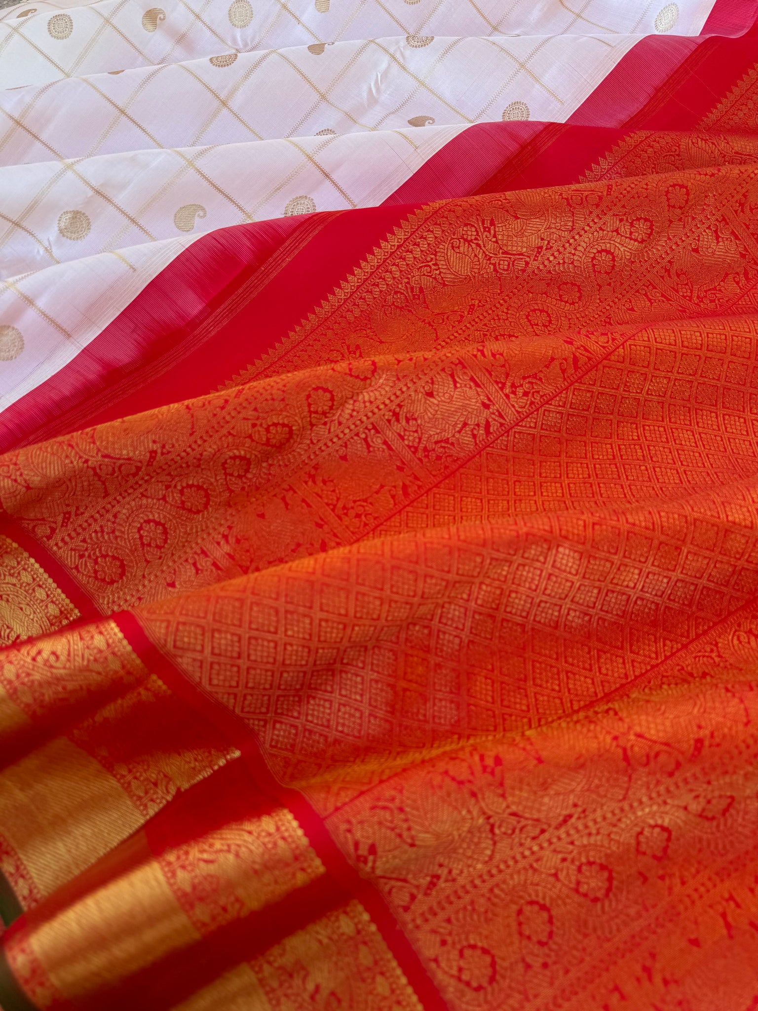 Statement of Kanchivaram - KK2 - one of kind and most fresh from the loom venn pattu ( pure tone of off white ) with red korvai woven solid gold borders with elephant motifs. The paisley and rudurakasham woven kattam buttas add more beauty to the sari !!