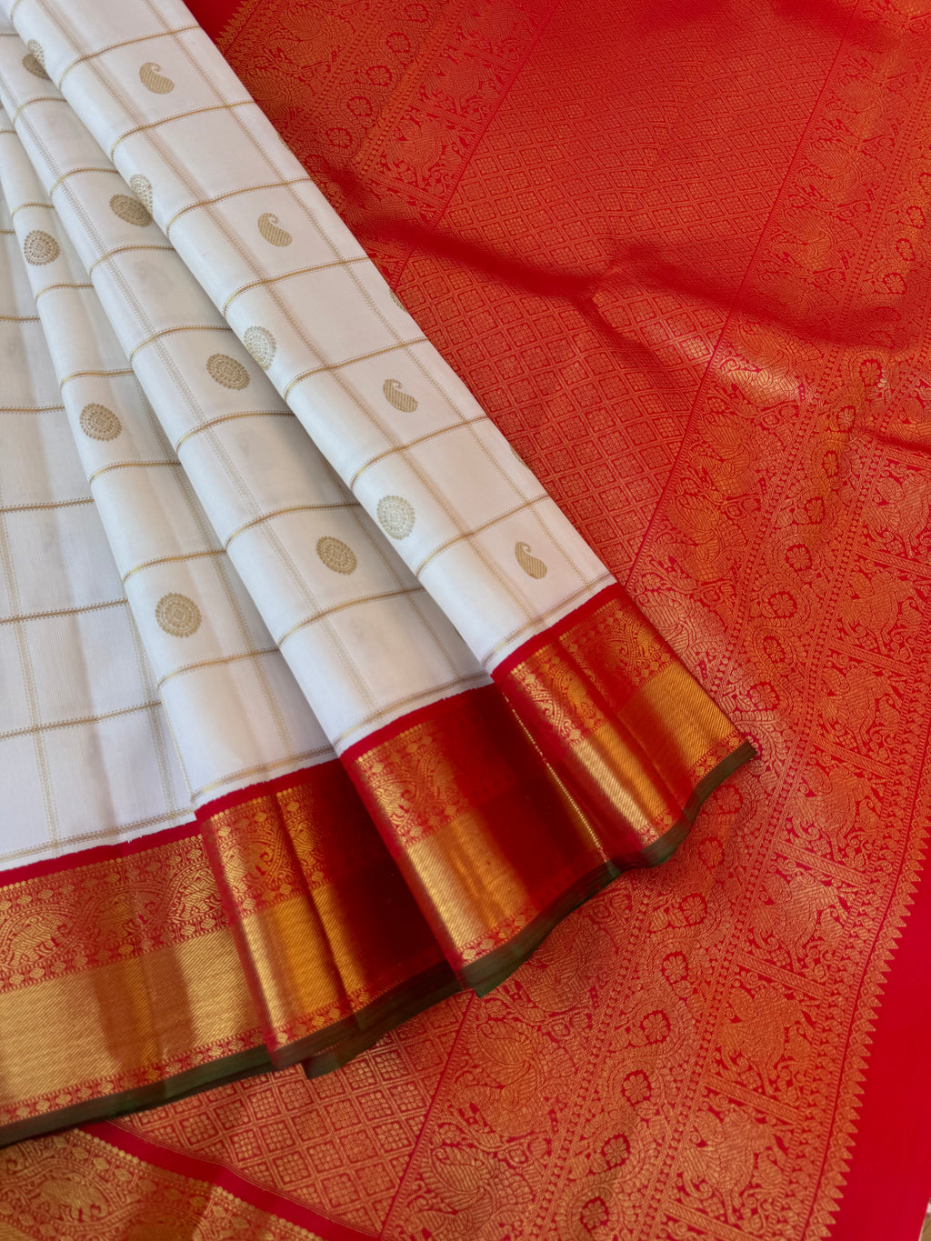 Statement of Kanchivaram - KK2 - one of kind and most fresh from the loom venn pattu ( pure tone of off white ) with red korvai woven solid gold borders with elephant motifs. The paisley and rudurakasham woven kattam buttas add more beauty to the sari !!