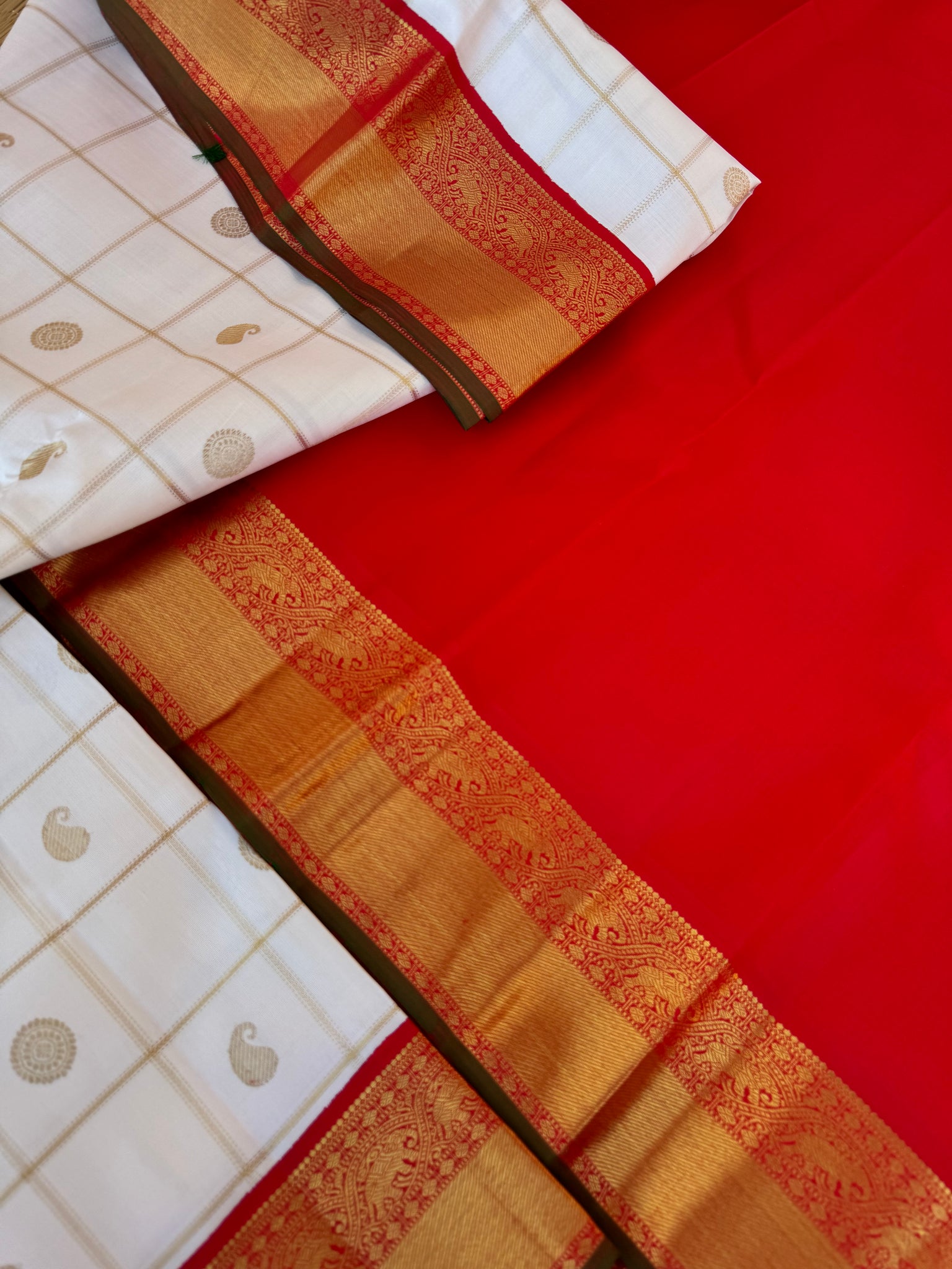 Statement of Kanchivaram - KK2 - one of kind and most fresh from the loom venn pattu ( pure tone of off white ) with red korvai woven solid gold borders with elephant motifs. The paisley and rudurakasham woven kattam buttas add more beauty to the sari !!