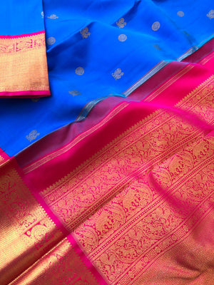 The Golden Treasure Of Kanchivaram - deeper anandha blue and rani pink with Mayil chackaram woven buttas all over the body, you can feel the gold in borders and pallu